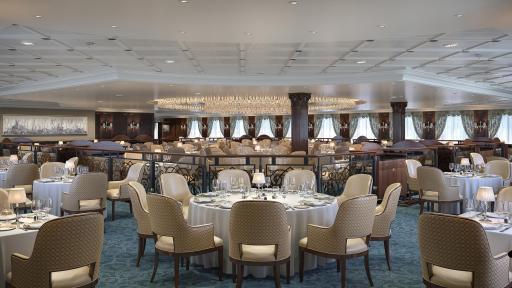 A large dining hall with chairs and tables that is the  The Grand Dining Room of the Regatta-Class ships