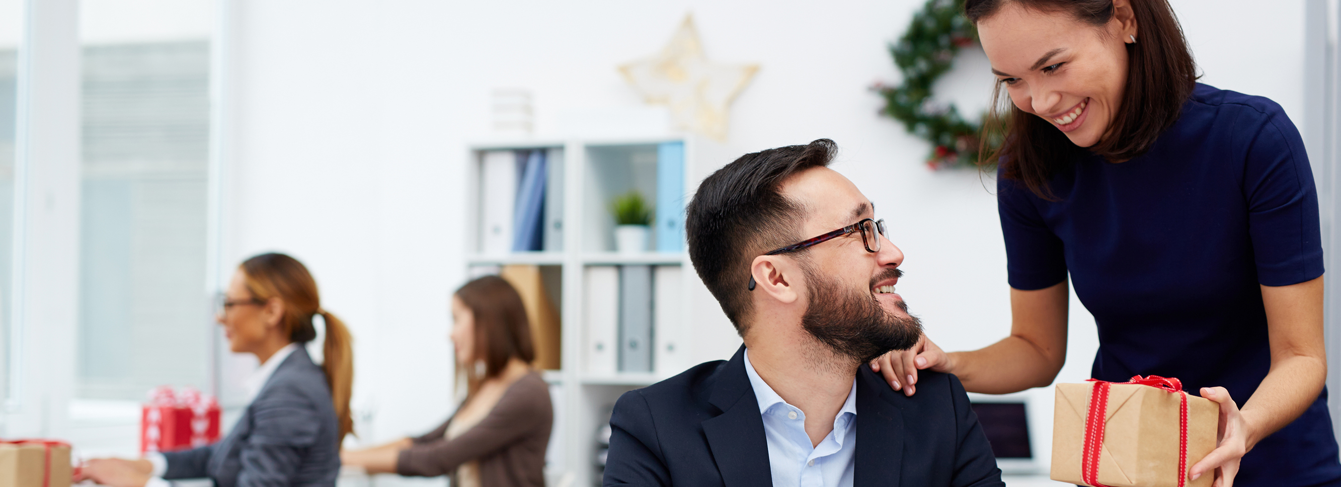 Woman giving a coworker a wrapped present