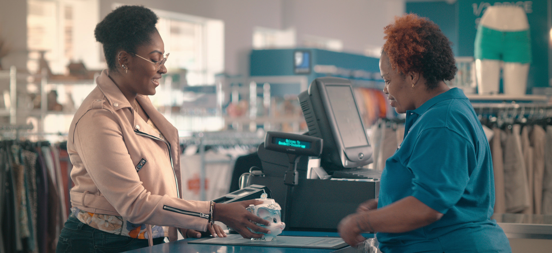 A woman purchases a vase from a goodwill cashier.