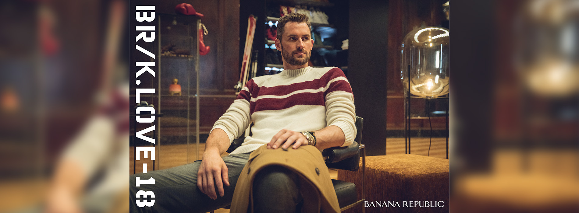 Image of K. Love lounging in a chair with a fashionable sweater.