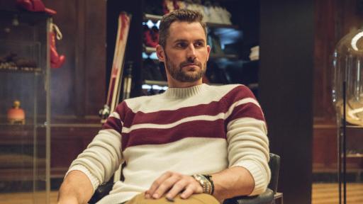 Man lounging in a chair with a fashionable sweater.