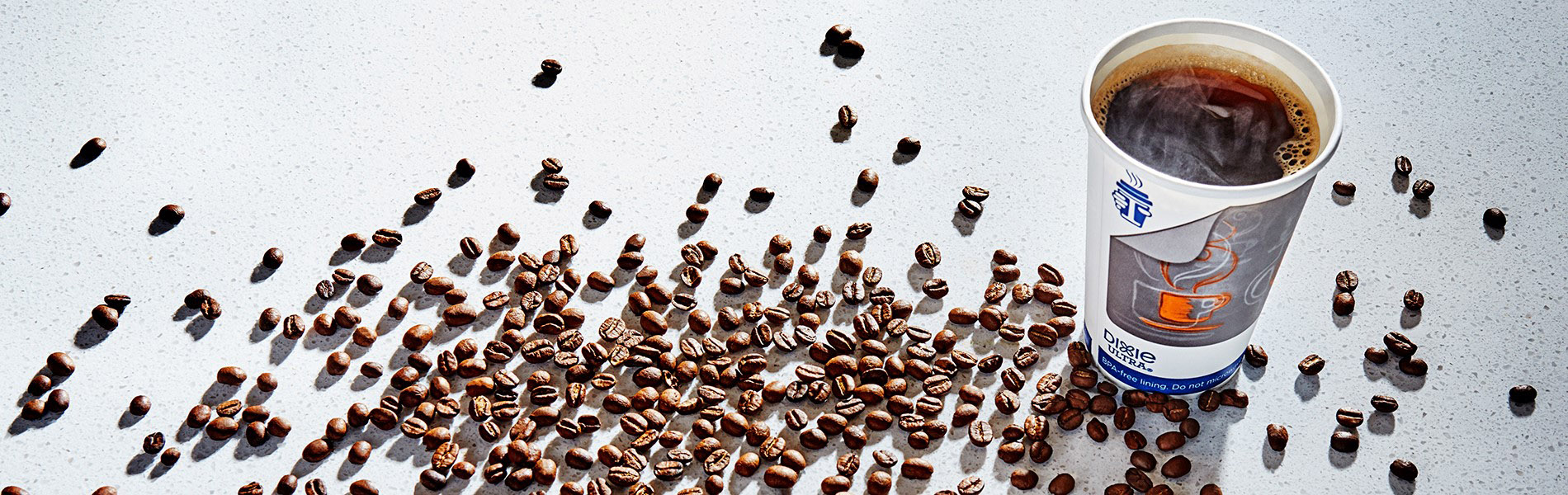 Insulair&trade; Hot Cup filled with hot coffee, coffee beans scattered around it