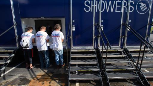 Three men on the outside of a trailer, washing their hands in sinks.