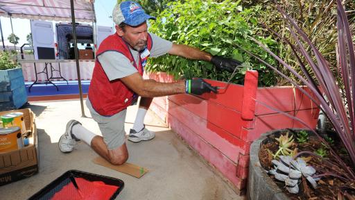 A member of Lowe's Heroes paints a garden bed red  at the Fairfield/Westside Boys & Girls Club.
