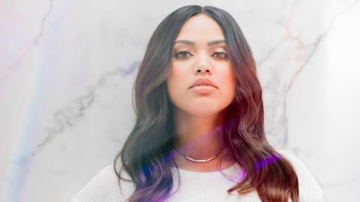 Ayesha Curry standing in front of a marbled backdrop