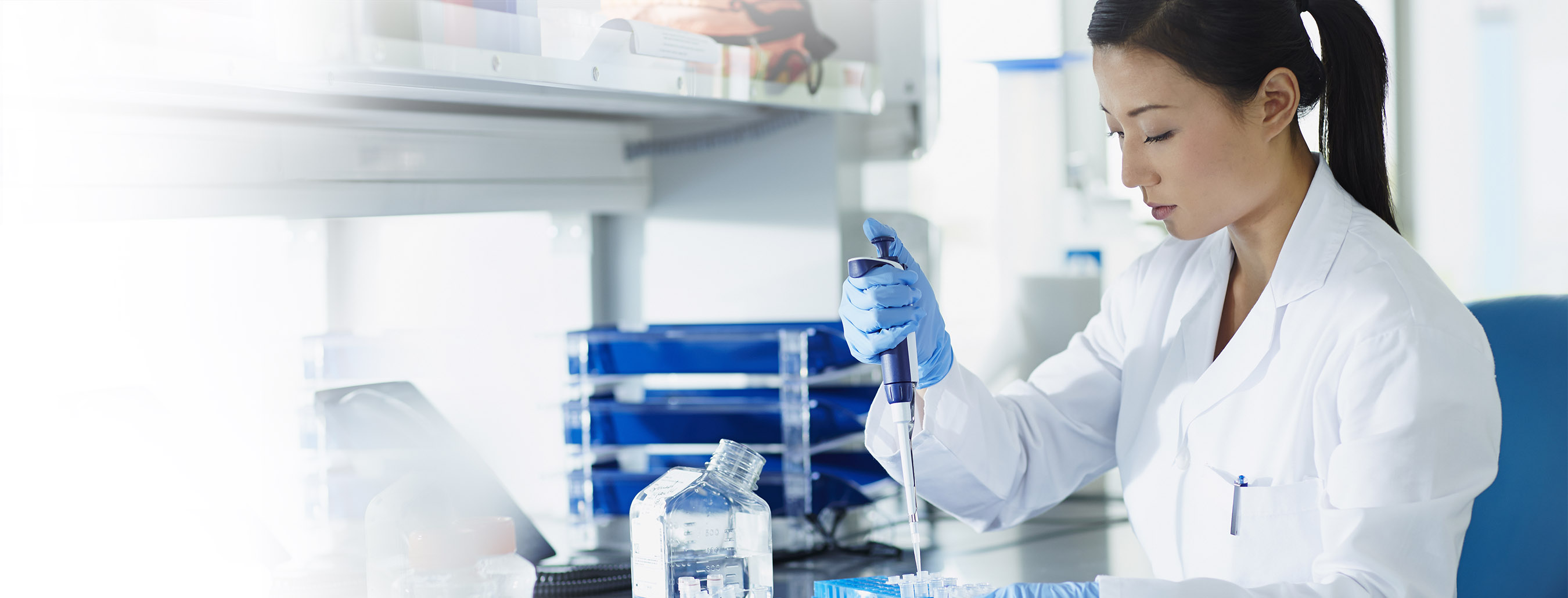 Sanofi, woman chemist fill a vile with a pipette.