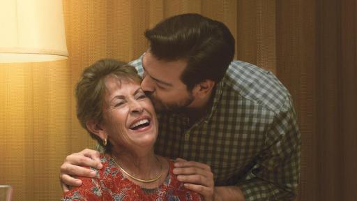 Man kissing his mother at the dinner table.