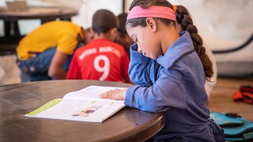 Young girl reading a book at a table