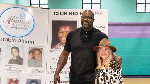 Shaquille O’neal standing in front of a large presentation poster in a blue gym.