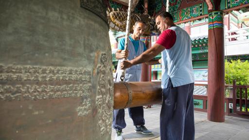 Two men ringing a very large temple bell.