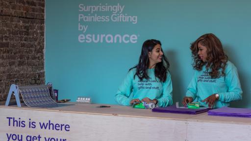 Esurance “Surprisingly Painless Gifting” pop-up shop ambassadors gift wrap presents with Dennis Quaid wrapping paper on December 13, 2018