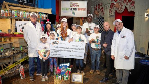 Contestants and judges pose with check.