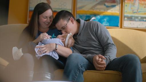 Mother holding child while father give the child a kiss