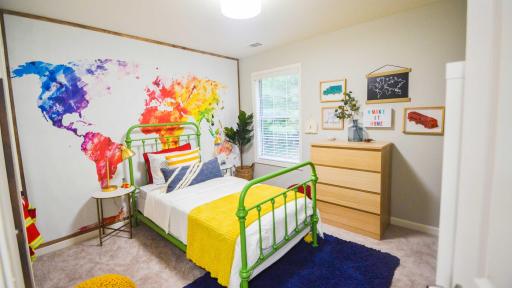 The children’s bedroom, designed by Erin Marshall of Living Pretty on a Penny, aims to show kids how big and bright the world is with a colorful map and added adorable organization ideas like a reading nook made with bookshelves