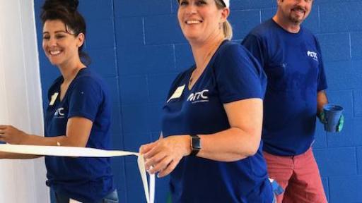Three ITC employees painting a room blue
