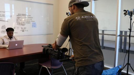 Men taking photo of man at desk