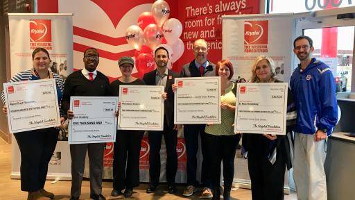 Six people with standing in line with Krystal awards checks