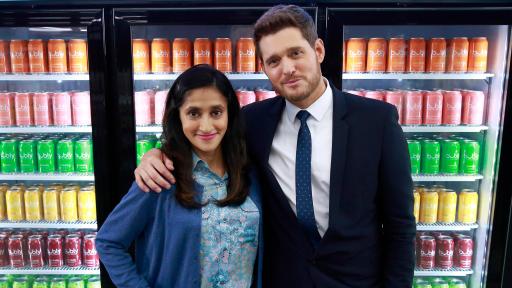 Aparna Nancherla and Michael Bublé standing in front of coolers of drinks.
