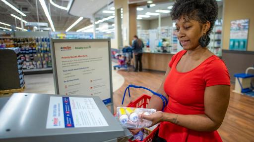 Women putting drugs inside Meijer drug take-back box