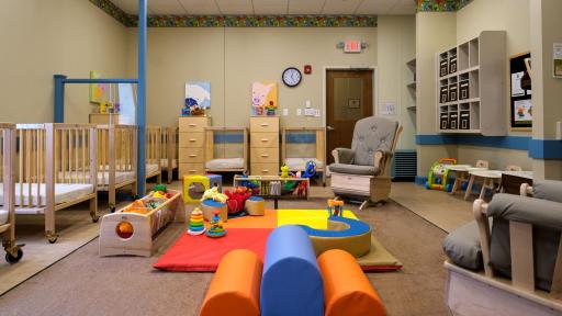 Infant classroom with colorful toys and beds
