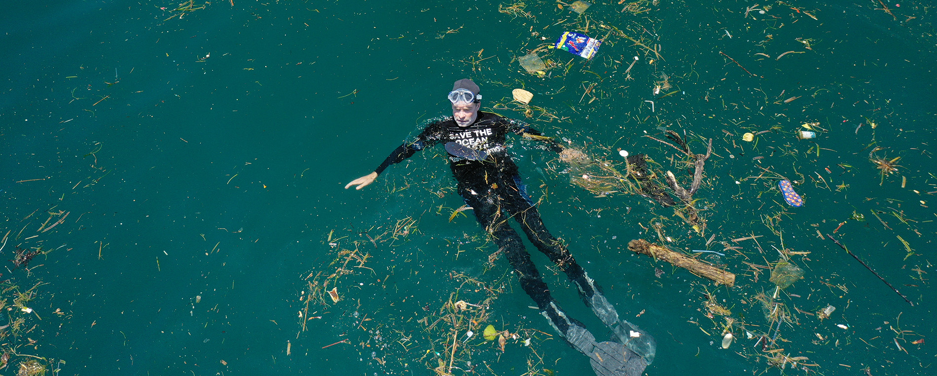 Fisk Johnson floating in the ocean surrounded by plastic debris