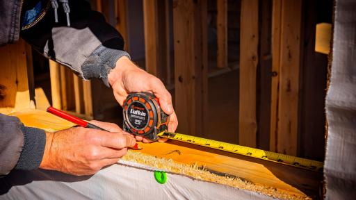 A worker using a tape measurer on a board