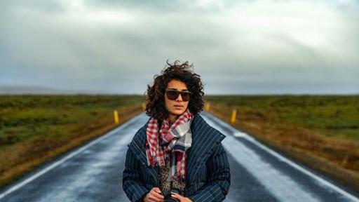 Asher Jay standing in road holding a camera.