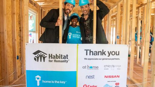 Three workers with Habitat for Huamnity standing behind sign inside under construction house they built displaying "Home Is The Key" and all the generous partners, including at home, chico's, nest, Nissan, O-Cedar, HGTV, and iHeart Radio.
