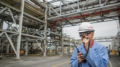 Man in a hardhat outside of a chemical plant.