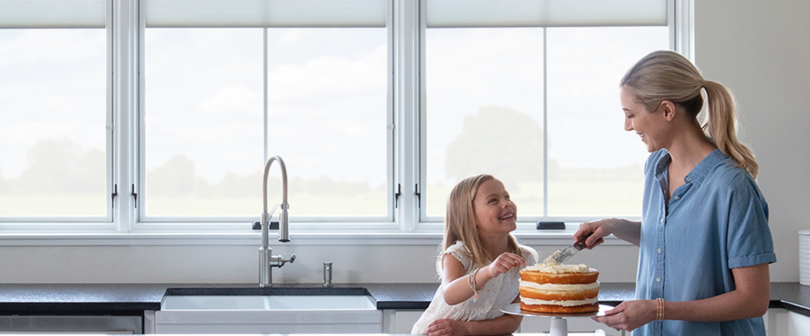 Mother and daughter icing a cake in a kitchen with Pella windows