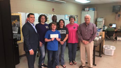 Group of people, one holding a check