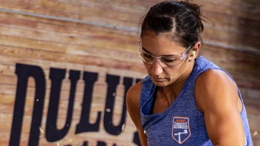 Erin LaVoie cuts a giant log with a chainsaw.