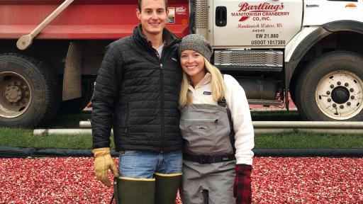 Becca and David stand in water filled with cranberries.