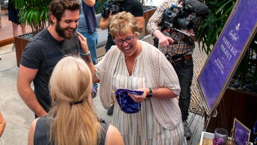 Man and woman laughing while woman holds purple bag