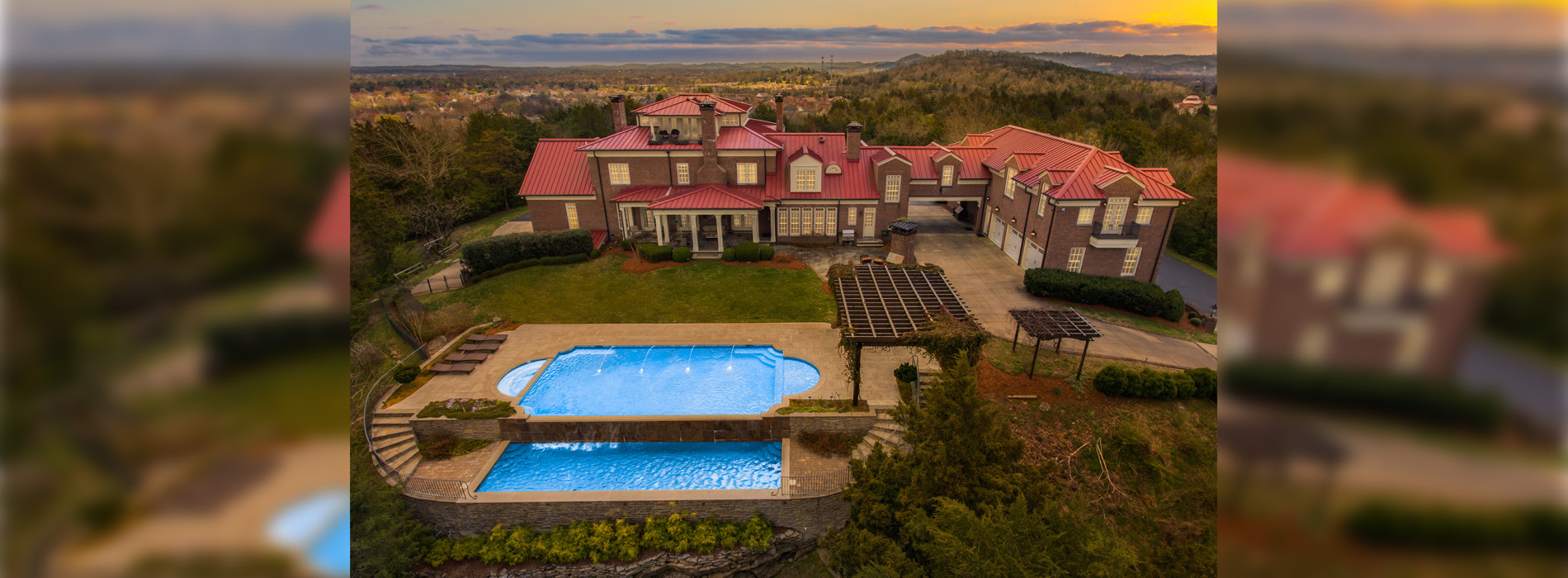 Large sprawling mansion with swimming pool in the dusk.