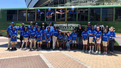 Kyle Larson poses with students from Meeting Street Academy next to the bus donated to the school by Credit One Bank and the NASCAR Foundation