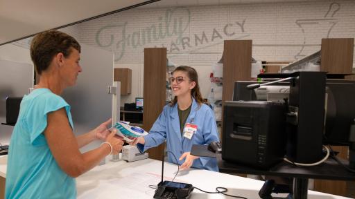 A pharmacist hands a man prescriptions