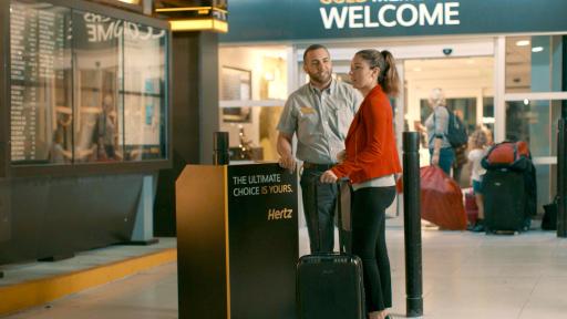 Woman with suitcase talking to a Hertz employee