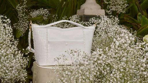 White purse on a stand surrounded by baby's breath flowers.