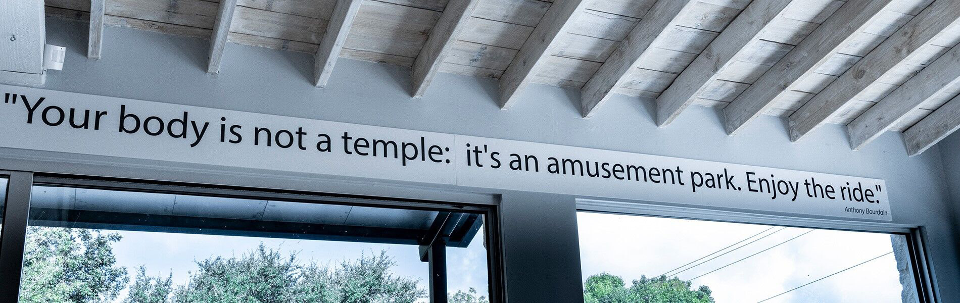 Sign above a door that says "Your body is not a temple: it's an amusement park. Enjoy the ride."