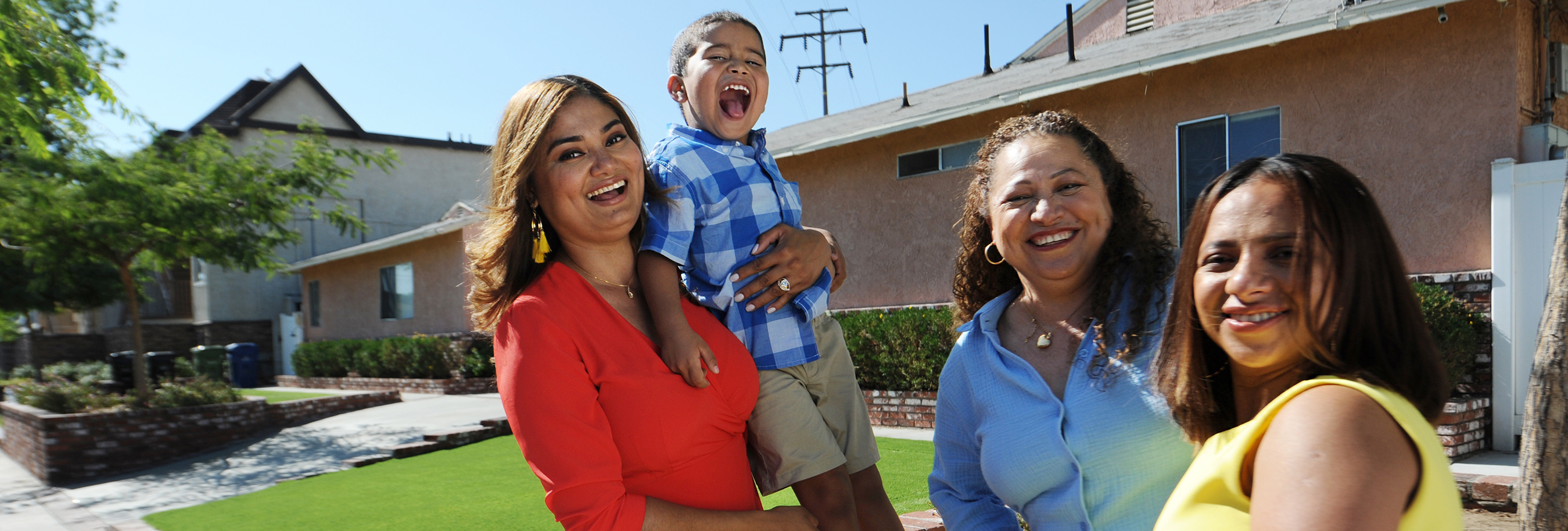 Women outside a home, one whom is holding a young boy.