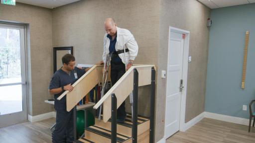 Therapist helping patient down stairs