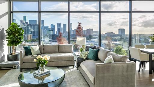 A luxurious apartment living room with a glass wall overlooking a cityscape.