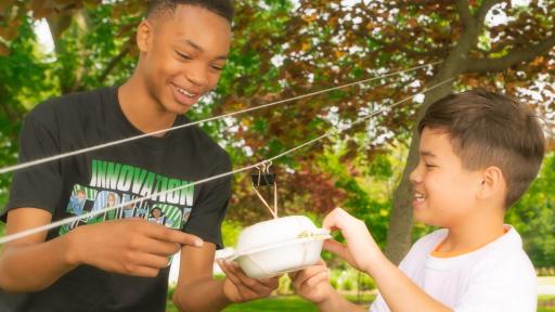 Two children playing with a miniature zipline.
