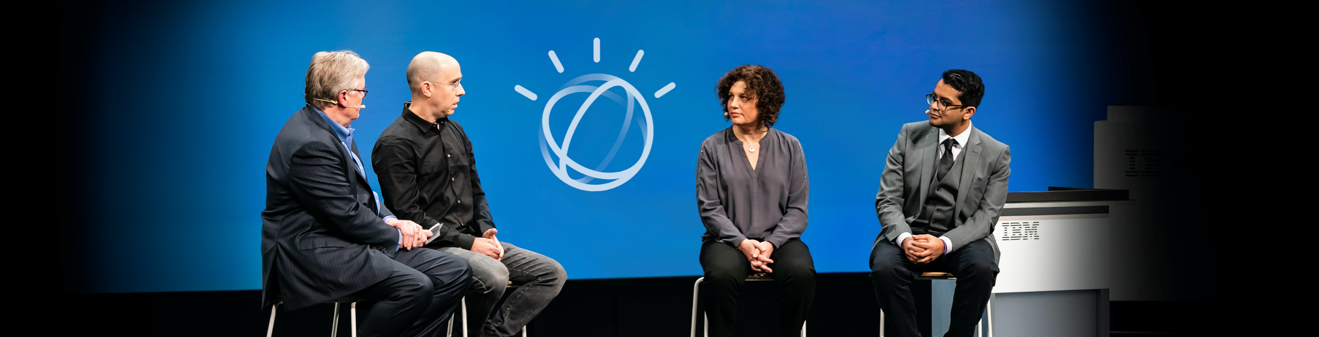 People on a stage sitting in uncomfortable chairs