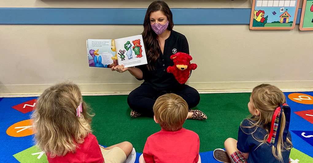 Woman telling a story with a book and animal puppet