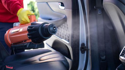 AutoBell worker cleaning the interior of a car with a disinfectant machine