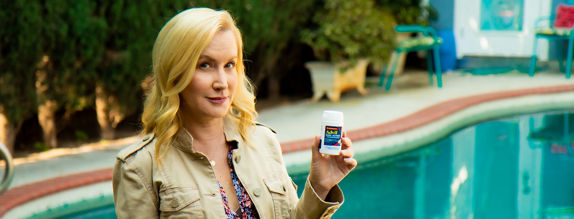 Woman holding a bottle of advil by a pool