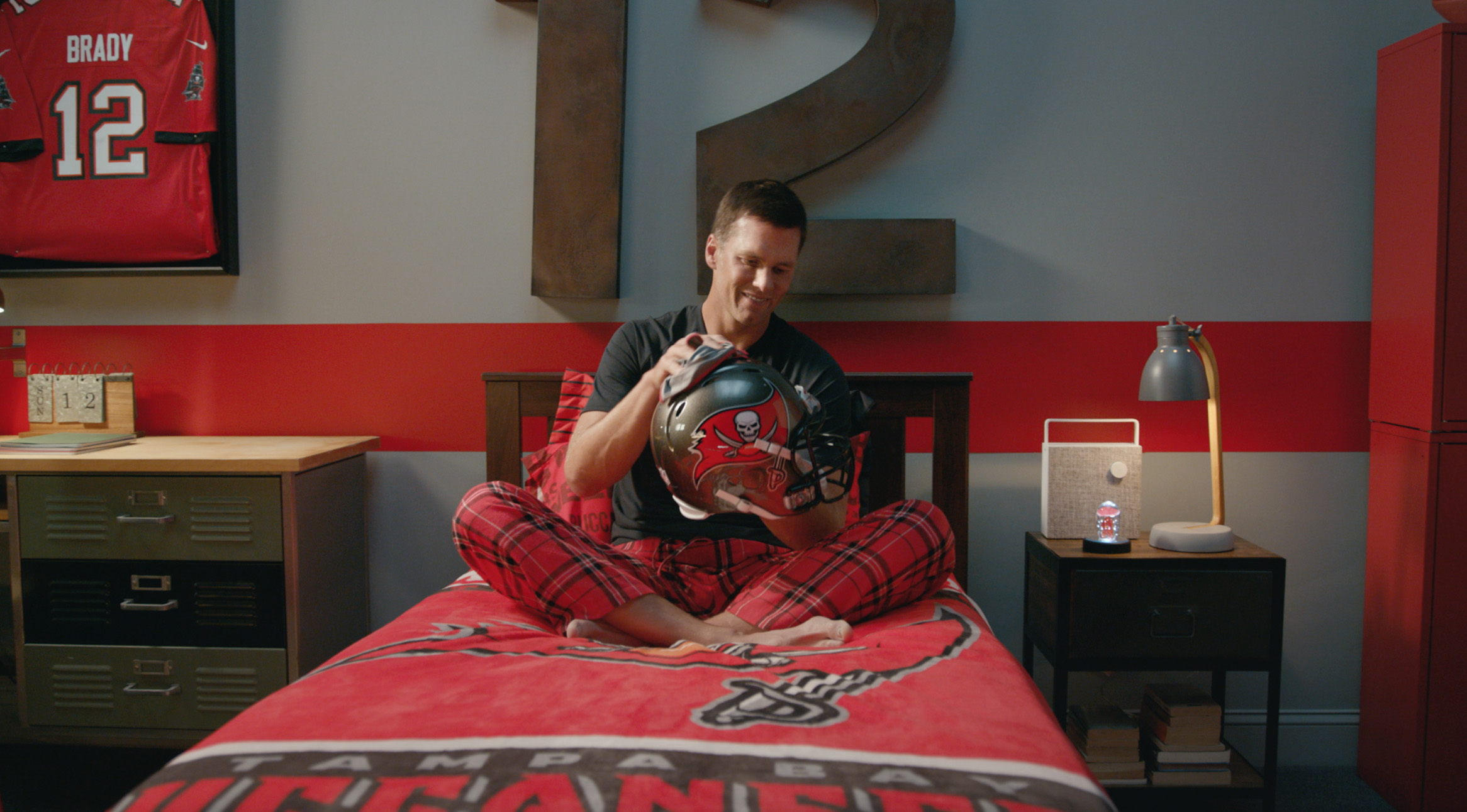 Brady sitting on a bed with football helmet in hand