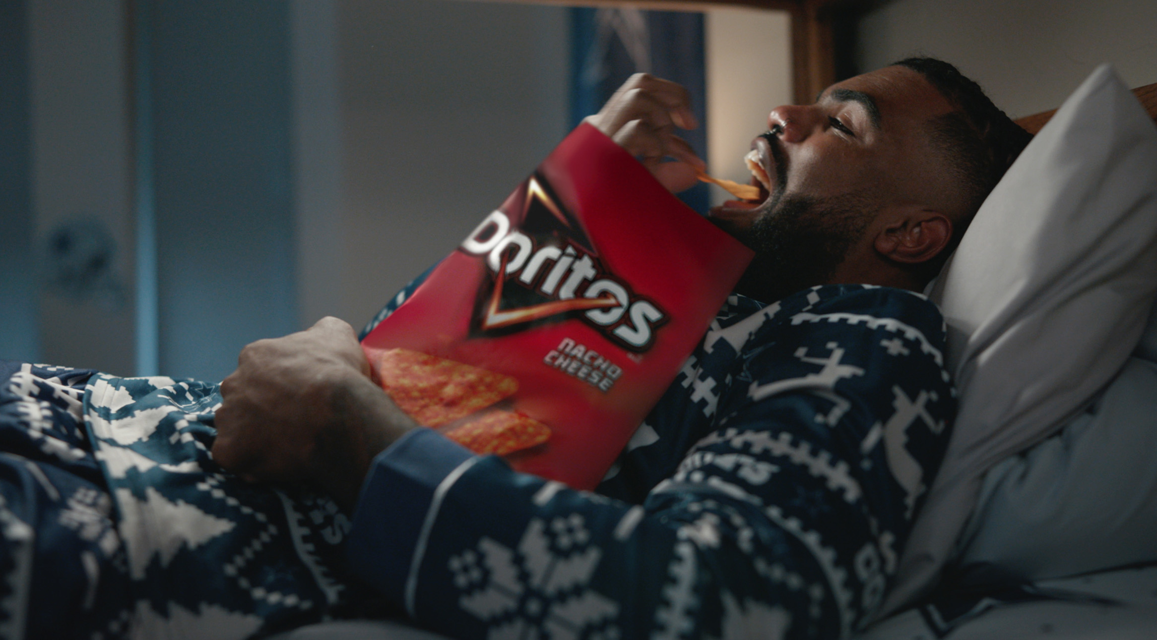 Zeke lying in bed and eating Doritos Nacho Cheese